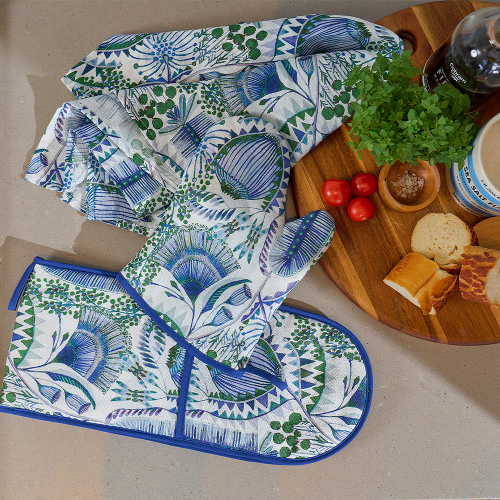 Set of blue and green patterned kitchen towels on a countertop with food items.