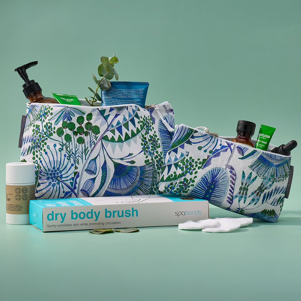 Cosmetic bag with skincare products and a dry body brush on a green background
