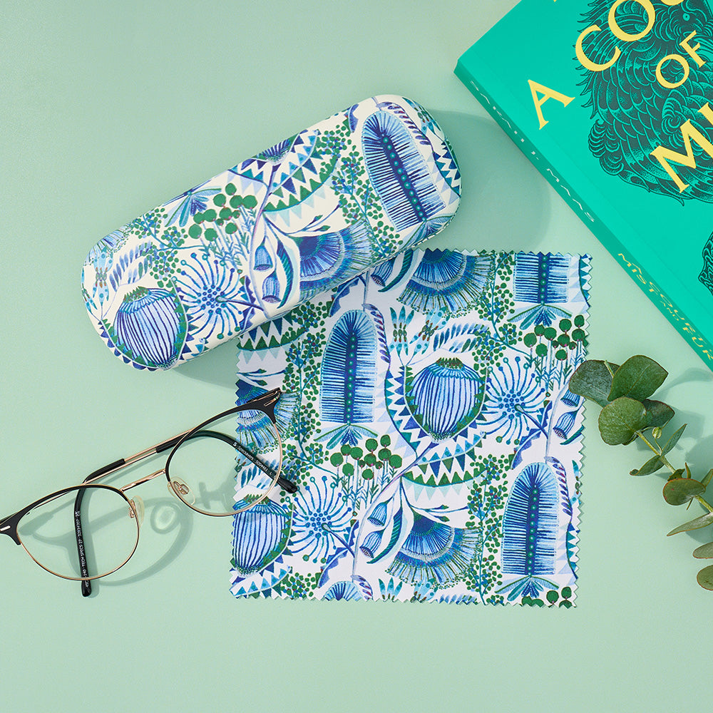 Patterned eyeglass case and sunglasses on a light green background with a book partially visible.