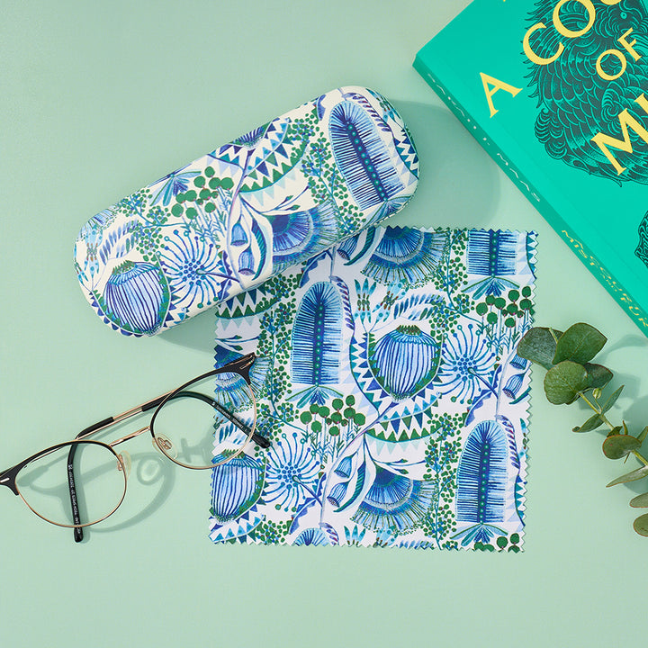 Patterned eyeglass case and sunglasses on a light green background with a book partially visible.
