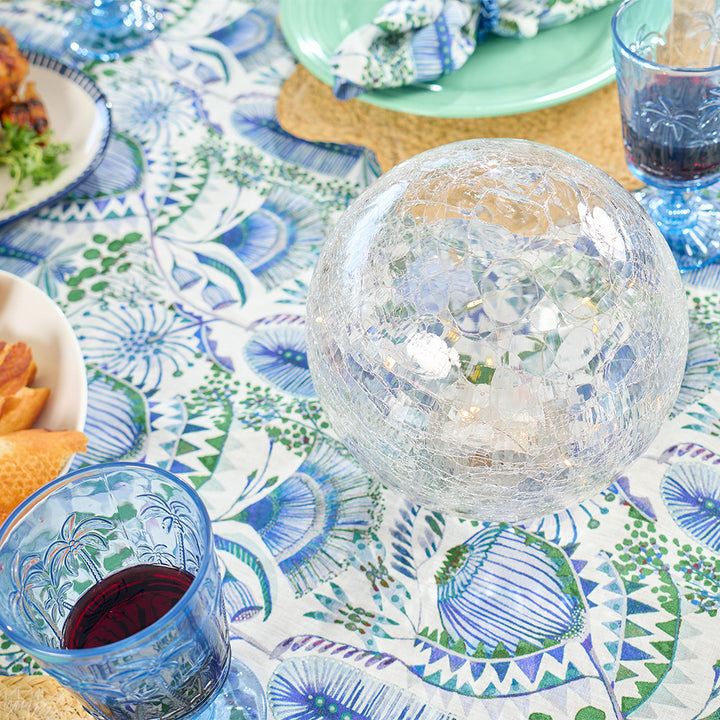 Decorative table setting with a crystal ball centerpiece on a patterned tablecloth.