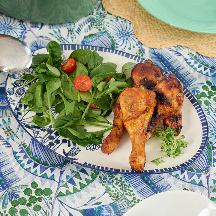 Plated chicken drumsticks with a side of salad on a patterned tablecloth