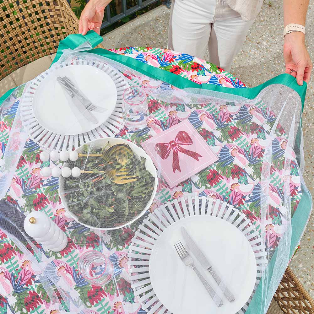 Floral-patterned tablecloth with cutlery and plates on a table with buzz off fly not covering table