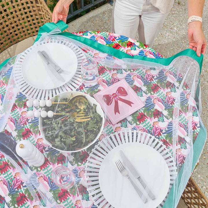 Floral-patterned tablecloth with cutlery and plates on a table with buzz off fly not covering table