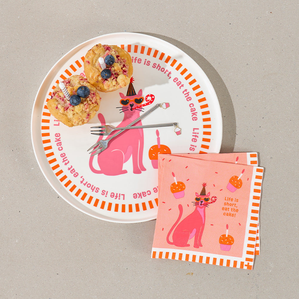 Plate with pink cat design, muffins, and napkin on a beige background