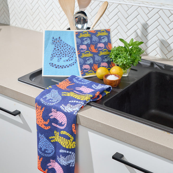 Colorful kitchen towels with animal patterns hanging over a kitchen sink.