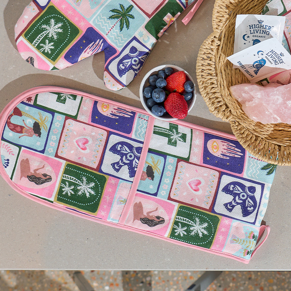 Colorful double oven mitt with various designs on a table with berries and a basket.
