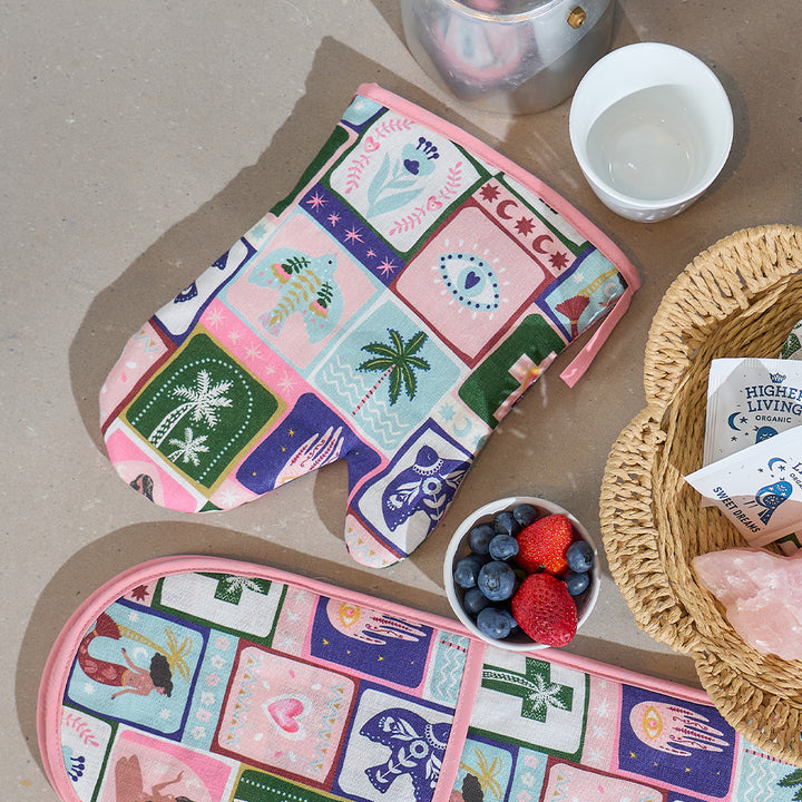 Colorful patterned pot holders on a table with a bowl of berries and a teapot.
