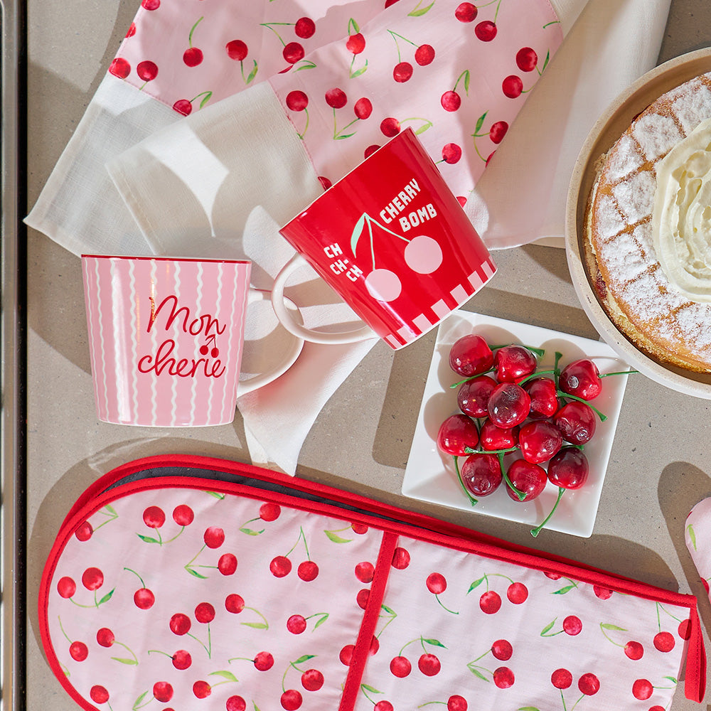 Cherry-themed kitchen items including mugs, oven mitts, and a pie on a table.