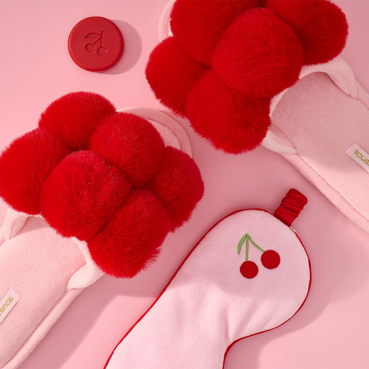 cherry and pink slippers with a mini soap and eye mask in the background