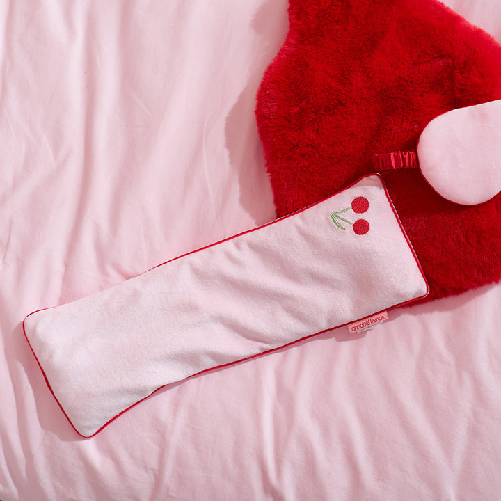 Red and white plush toy with cherry design on a pink background