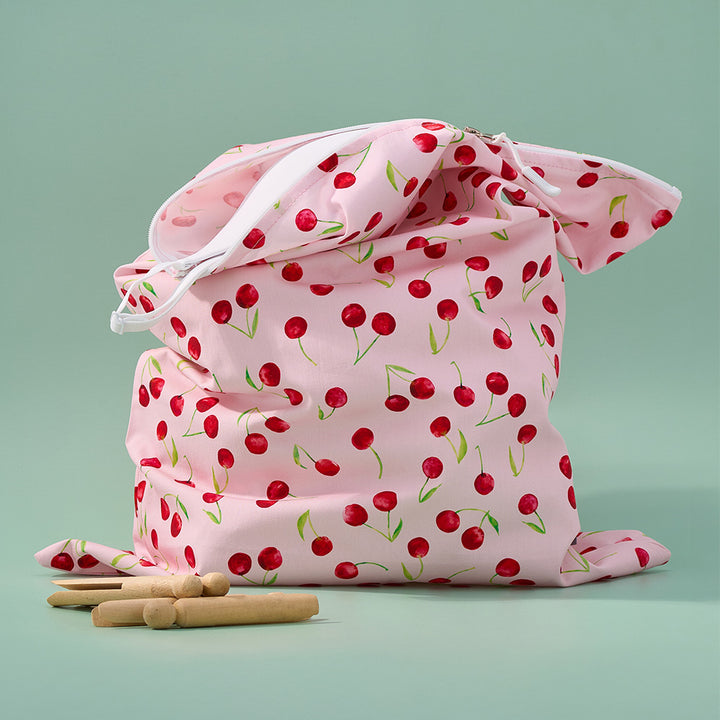 Pink laundry bag with cherry pattern on a light green background