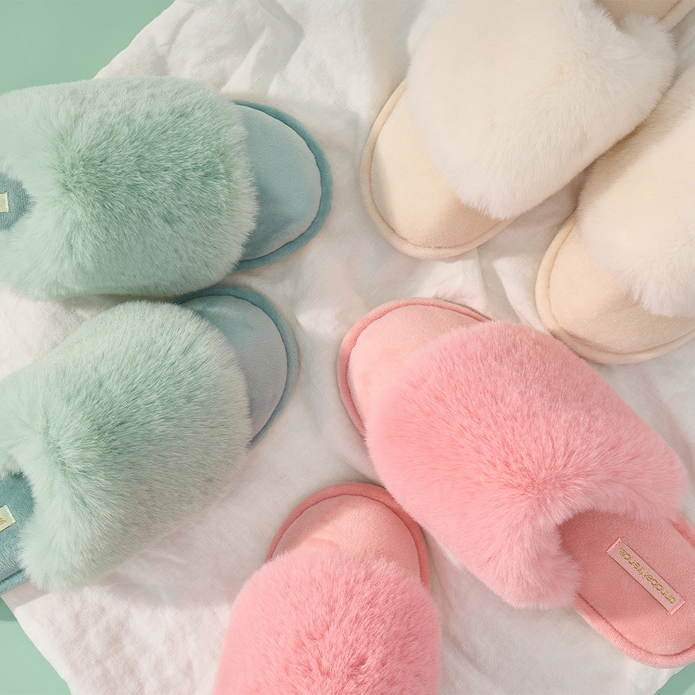 Pair of pastel-colored fluffy slippers on a soft surface