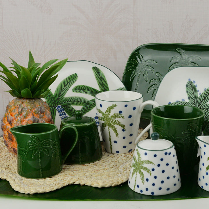 Set of ceramic mugs and dishes with palm tree design on a white background