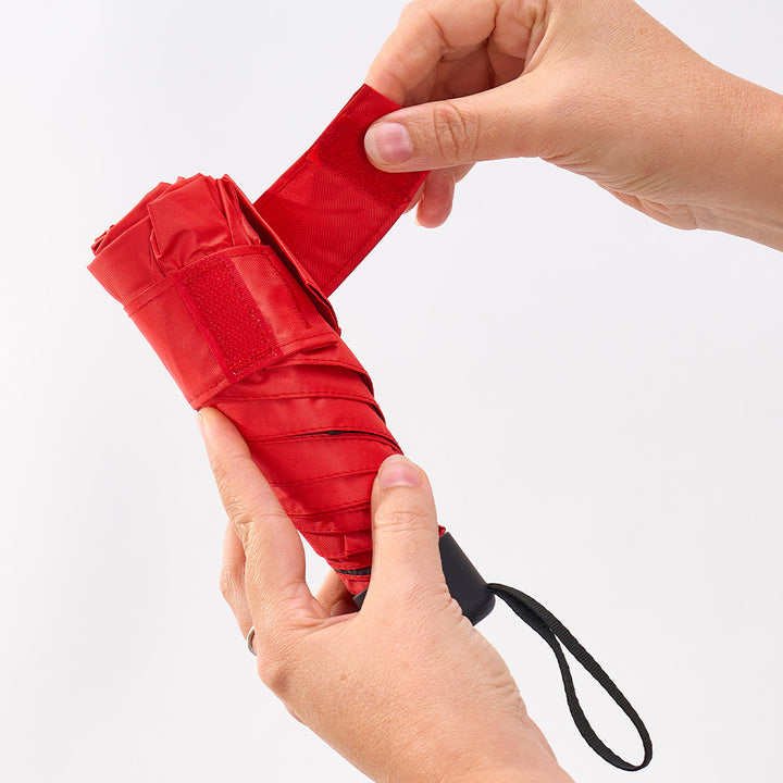 Red umbrella being held by a person's hands against a white background