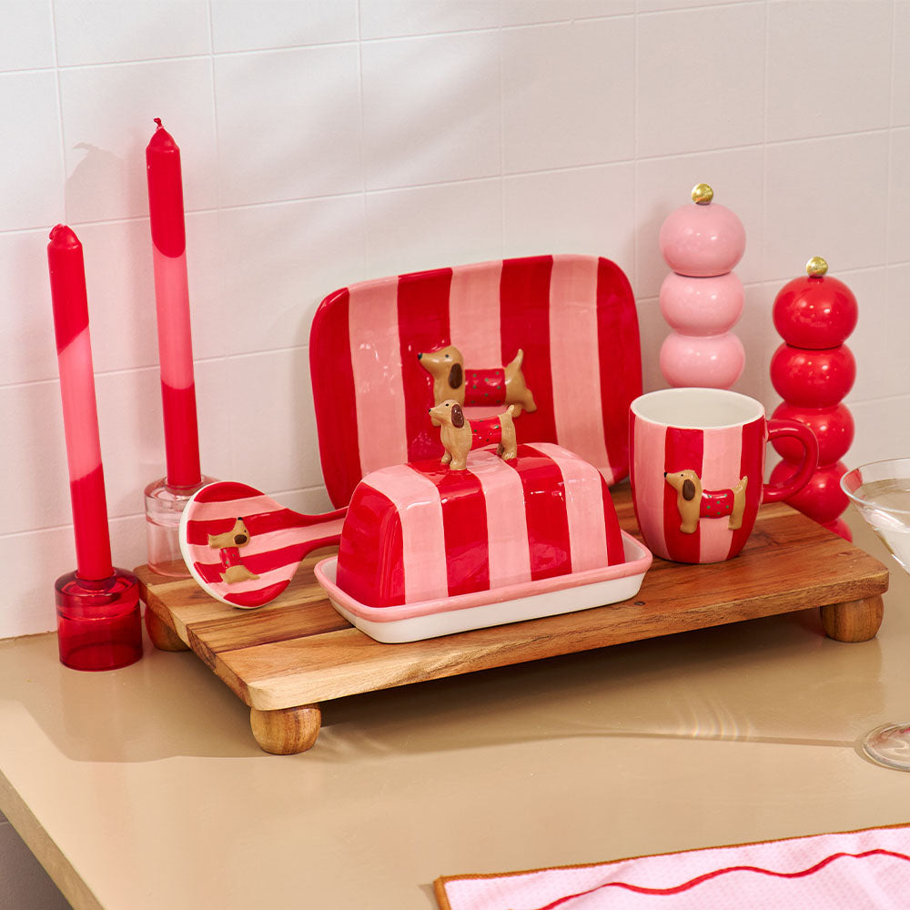 Red and white striped dish set with matching candle and salt and pepper shakers on a wooden tray.