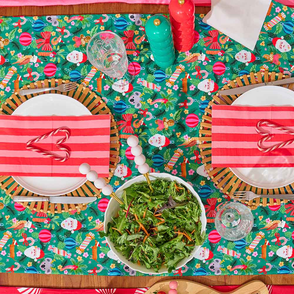 Colorful Christmas-themed table setting with a salad in the center.