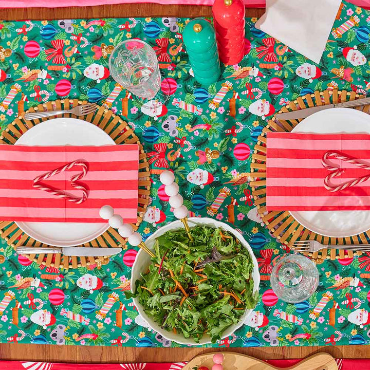 Colorful Christmas-themed table setting with a salad in the center.