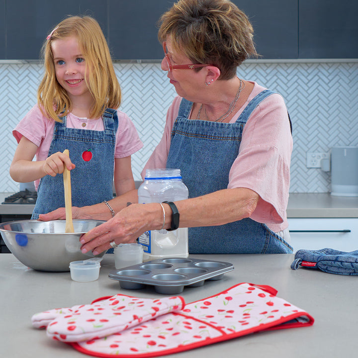 Woman and young girl in a kitchen preparing food, wearing denim aprons.