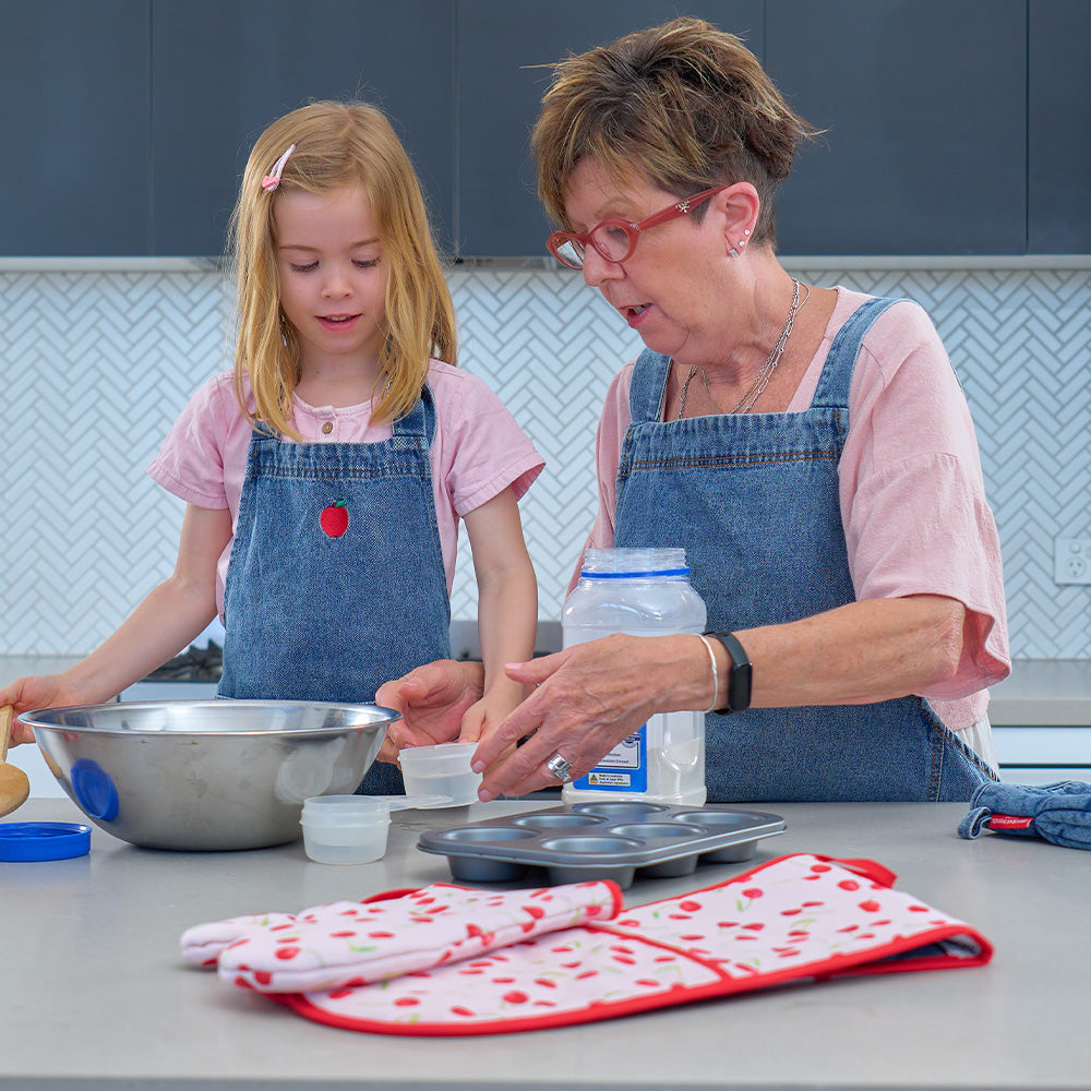 Grandmother and granddaughter in a kitchen preparing food together.