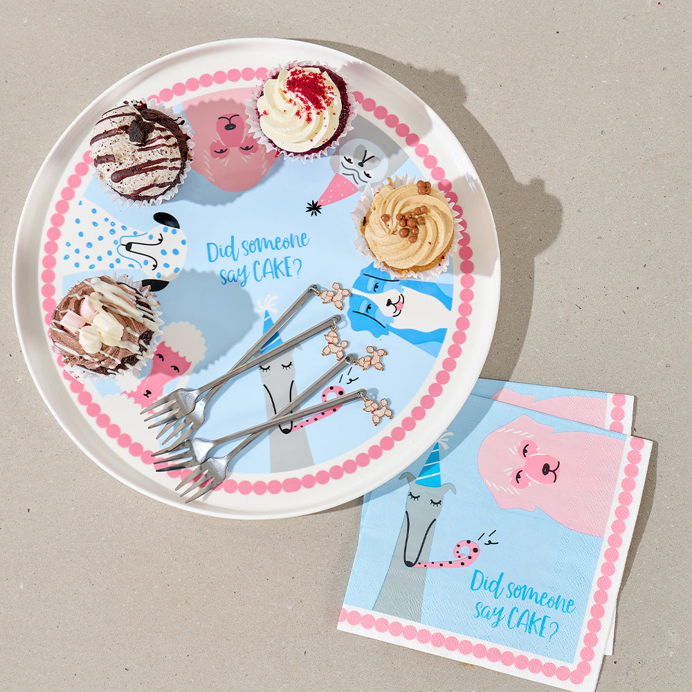 cake serving plate with dog cartoon cakes and napkins on a beige surface