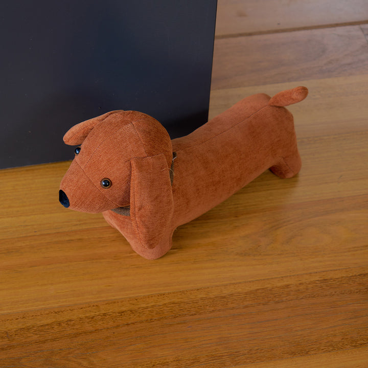 Plush dachshund doorstop on a wooden surface