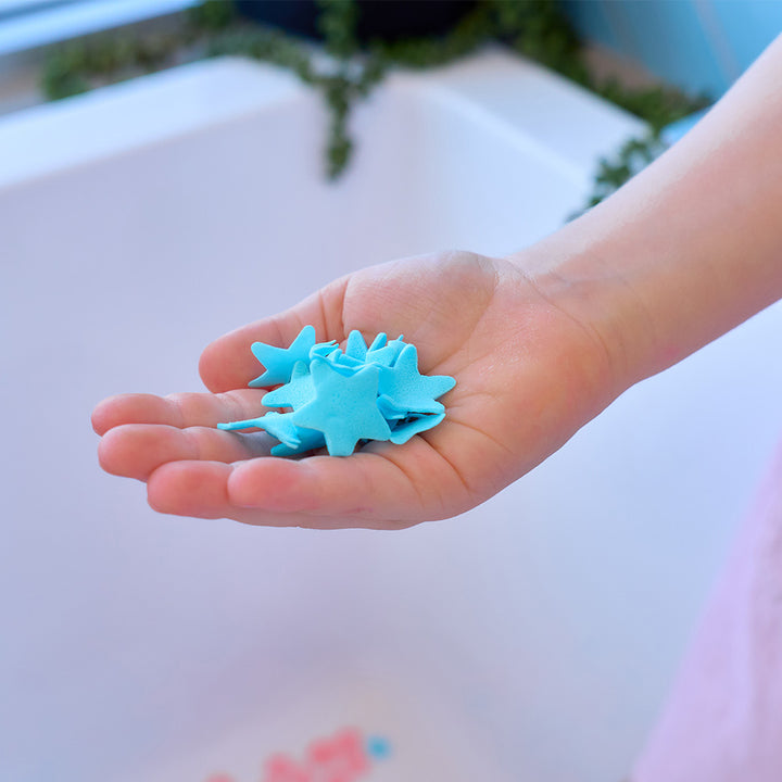 Child's hand holding blue star-shaped objects with a blurred background