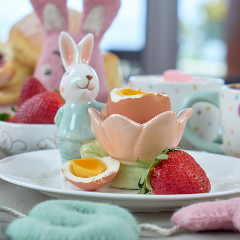 Ceramic bunny cup with an egg and strawberry on a plate with Easter-themed background