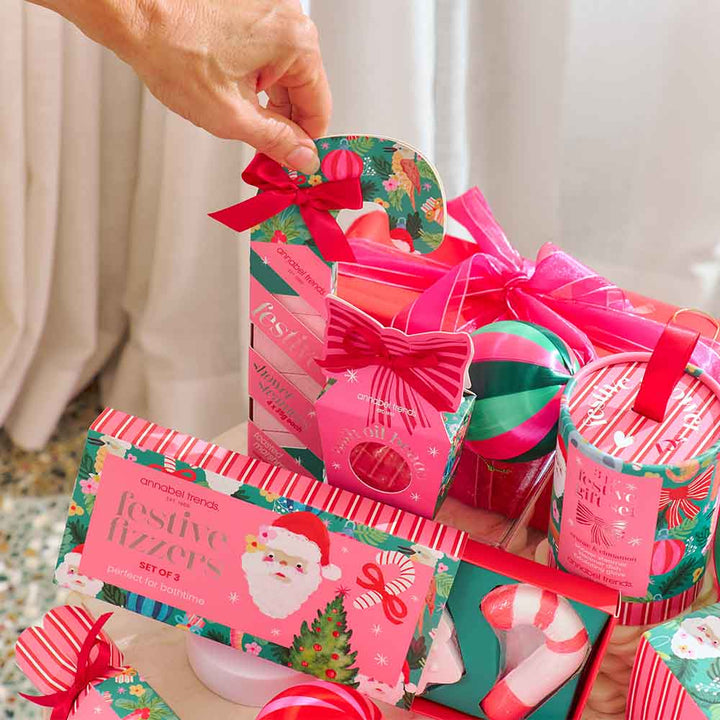 Collection of festive gift items including soaps and bath bombs on a table.