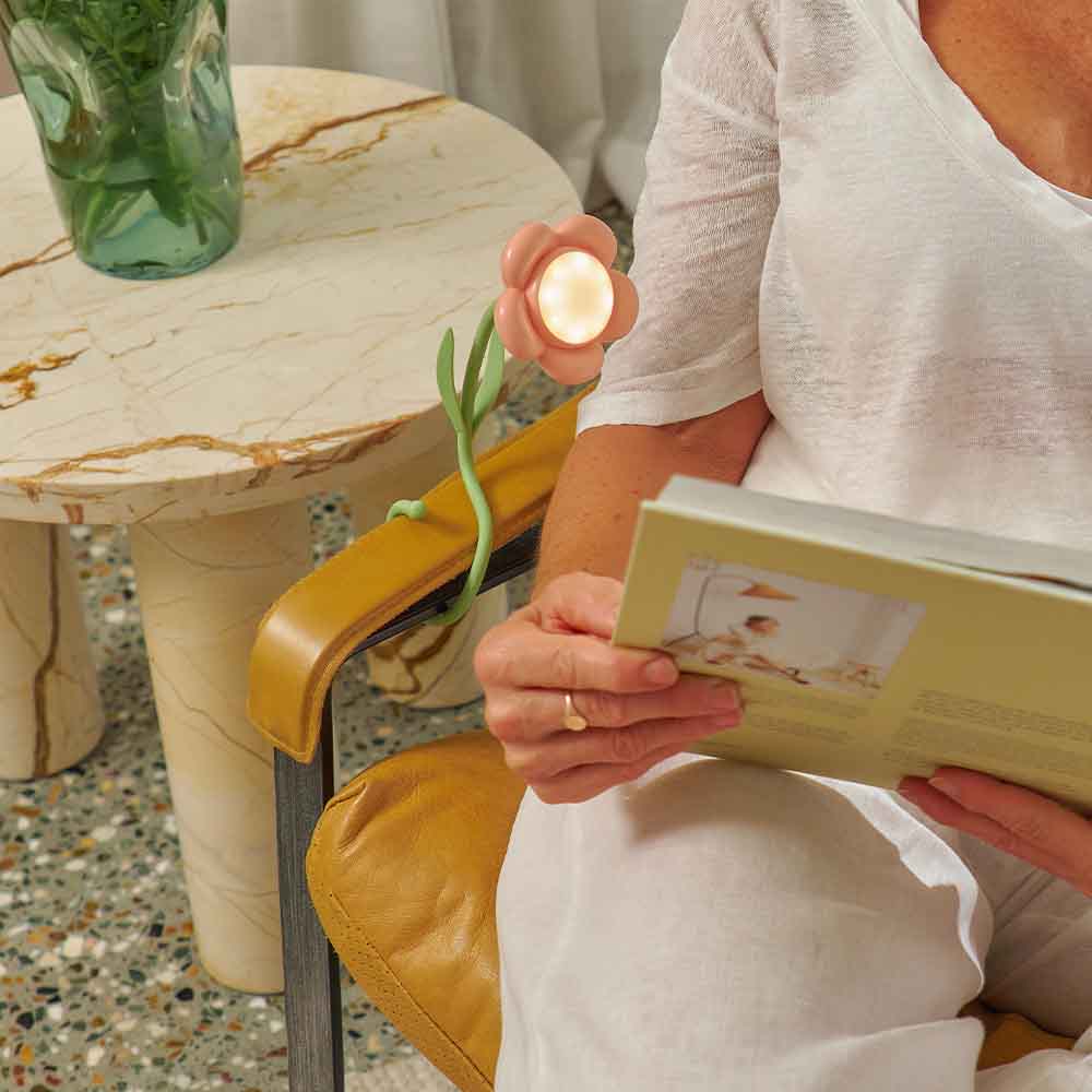 Person holding a book with a small candle and plant on a marble table.