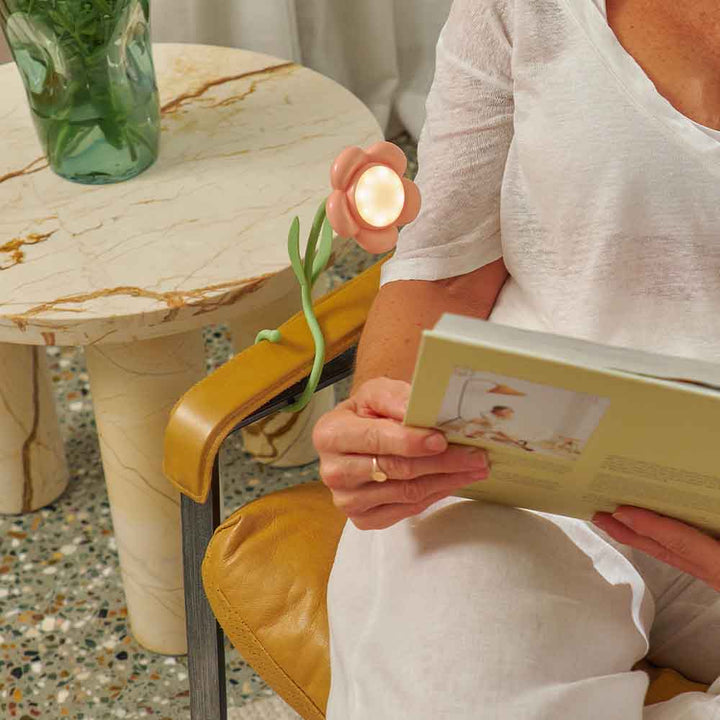 Person holding a book with a small candle and plant on a marble table.
