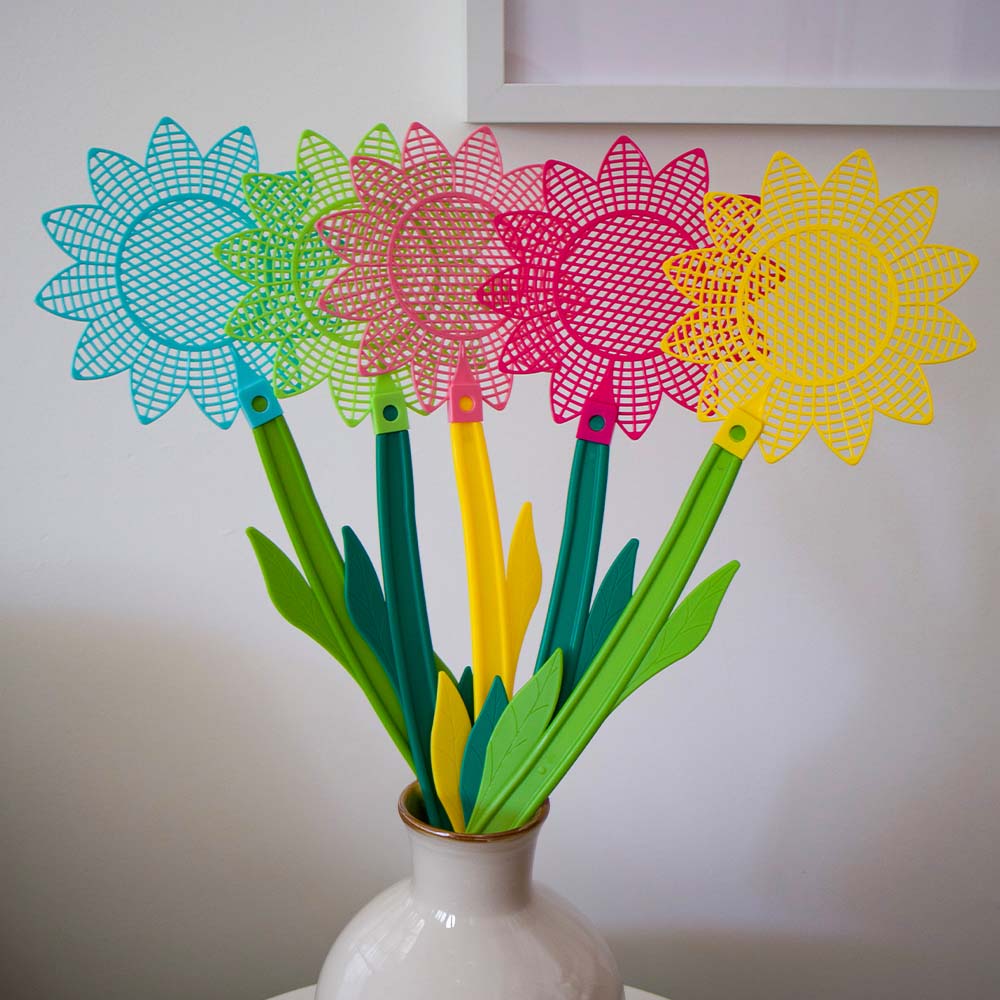 Colourful  flower shaped fly swatters in a white vase against a plain background