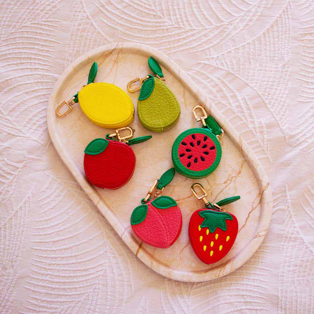 Colorful fruit-shaped keychains on a textured surface