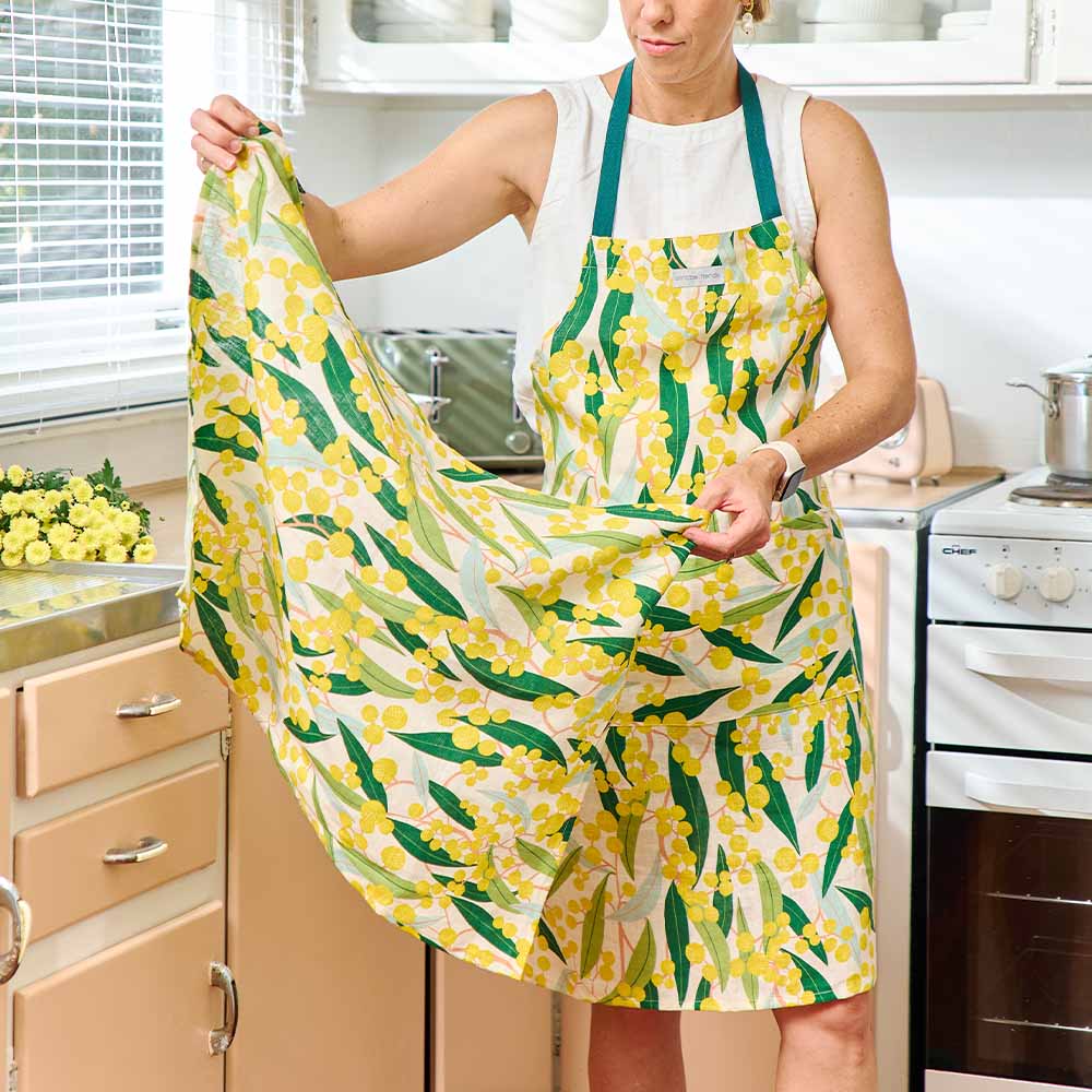 Person wearing a yellow floral apron in a kitchen