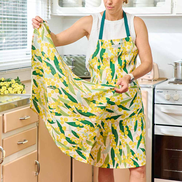 Person wearing a yellow floral apron in a kitchen
