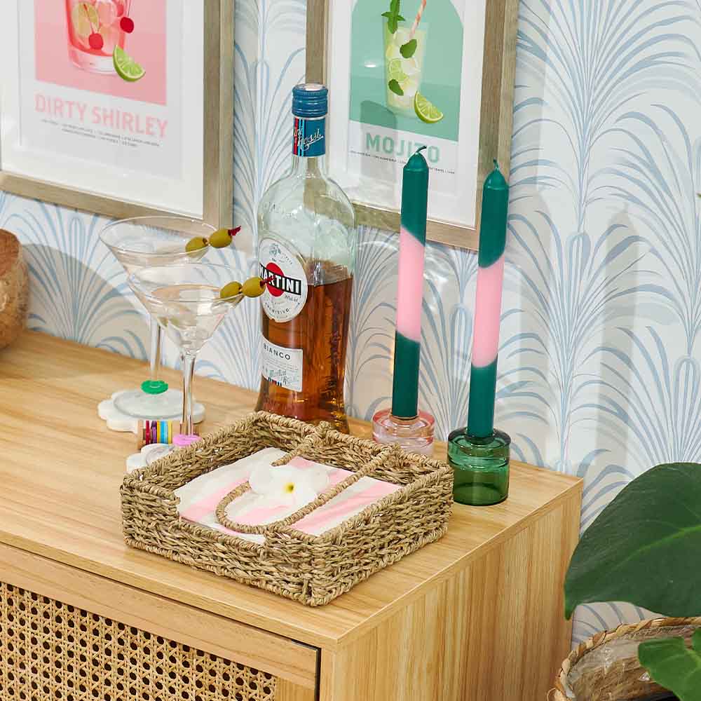 Bar setup with bottles, glasses, and candles on a wooden surface with decorative wall art in the background.
