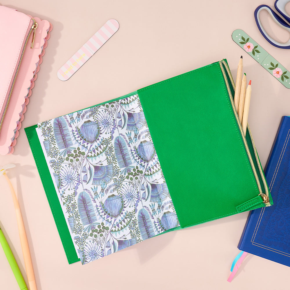 Green notebook with floral pattern on a desk with stationery items