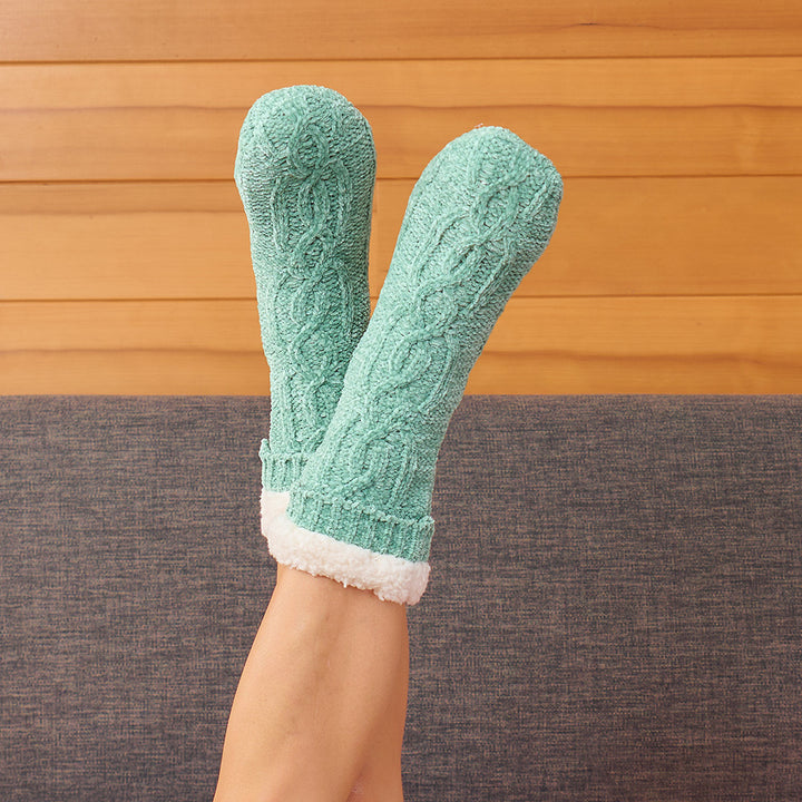 Teal cable knit socks with white cuffs and toes worn by a person against a wooden floor.