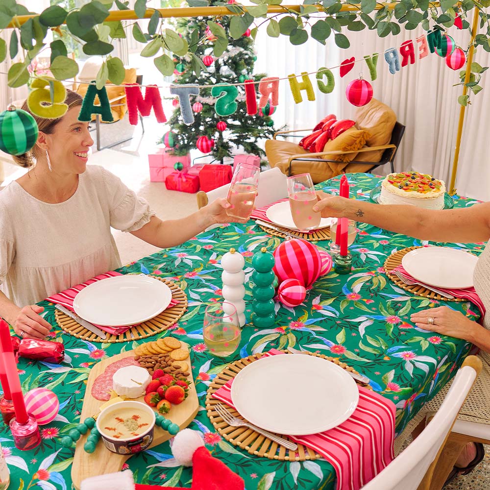 People celebrating Christmas at a decorated table with festive decorations and a Christmas tree in the background.