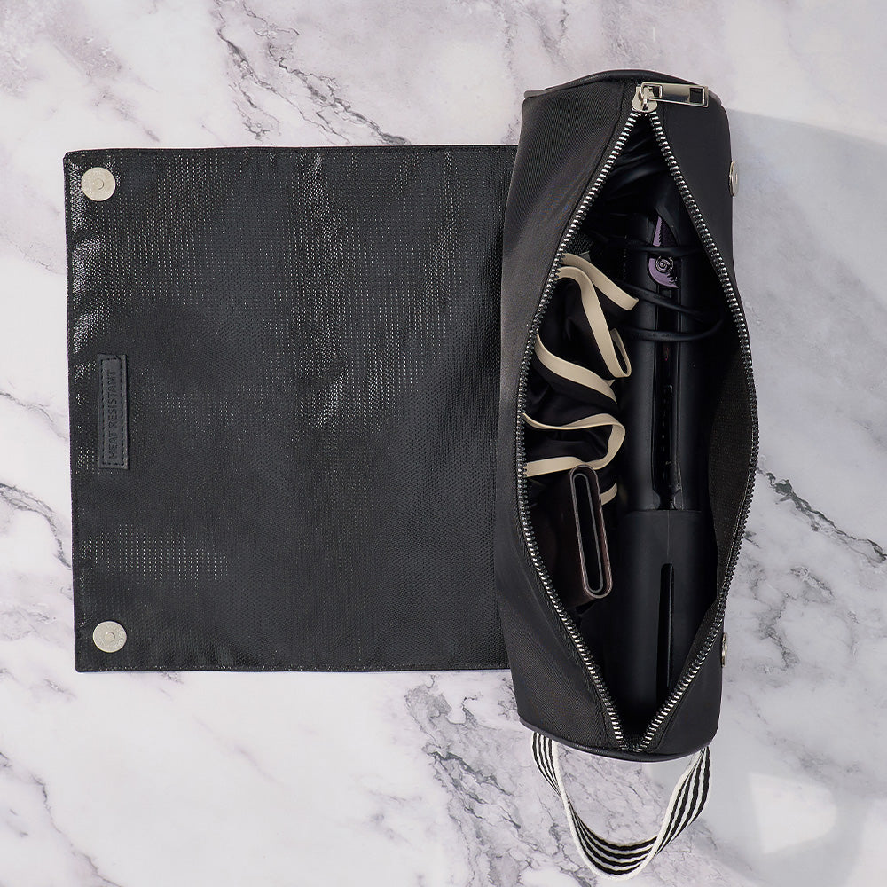 Black leather bag with a pen and accessories on a marble surface