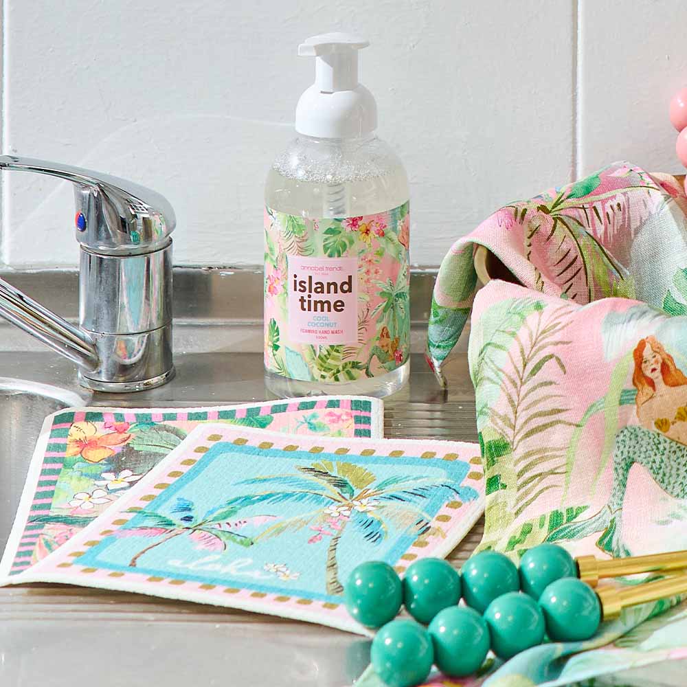 Kitchen sink area with floral-themed towels, soap bottle, and green berries.
