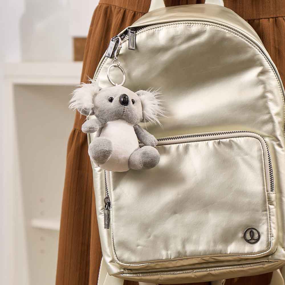 Silver backpack with a koala plush toy attached to it