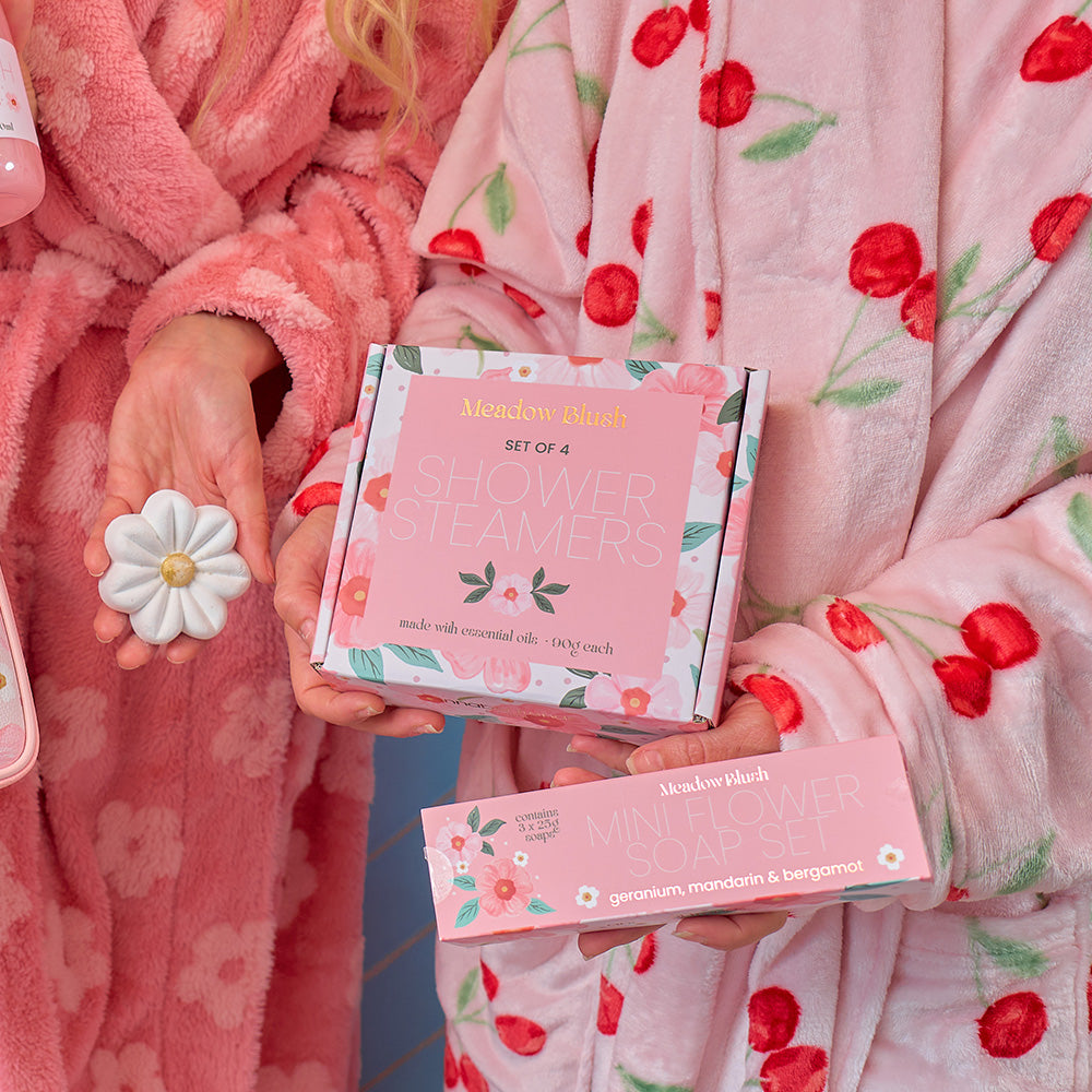 Person in a pink robe holding a set of Meadow Bird bath bombs and packaging.