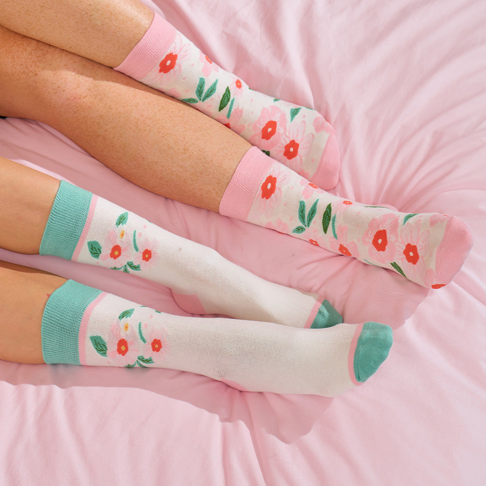 Floral calf-high socks with pink and green accents on a pink surface