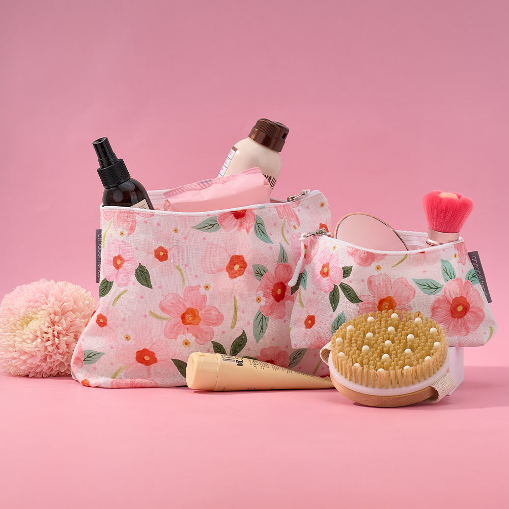 Floral-patterned cosmetic bag with skincare products on a pink background