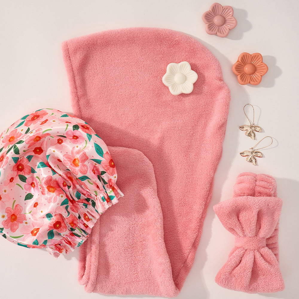 Pink hair towel set with floral bonnet and hair accessories on a light background