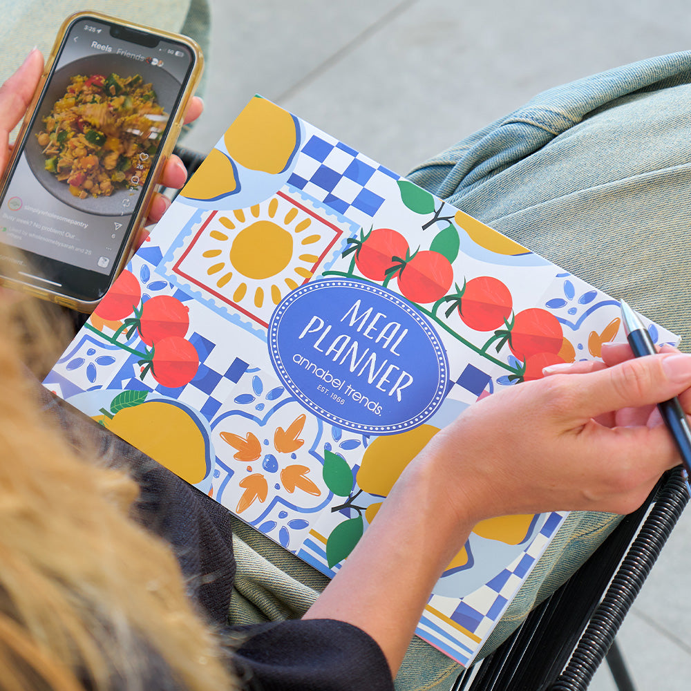 person holding meal planner with taste of sicily design on the front cover