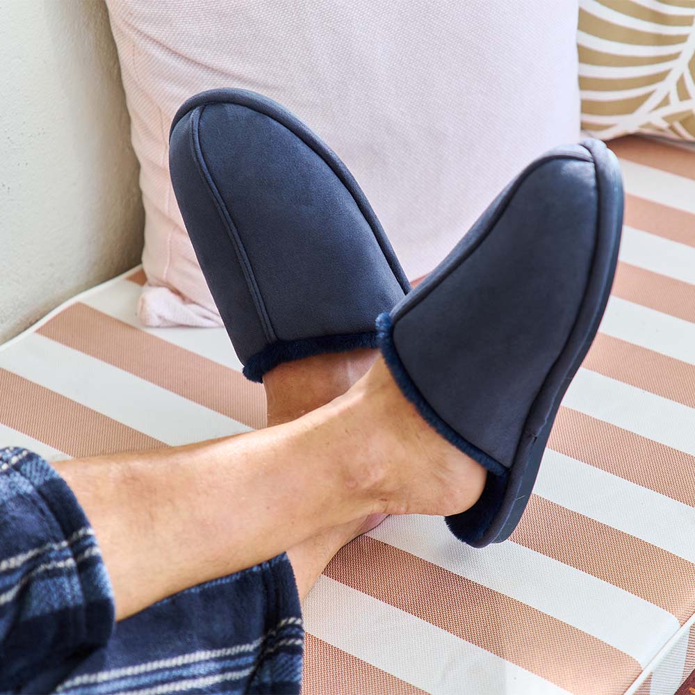 Person wearing navy blue slippers on a striped couch