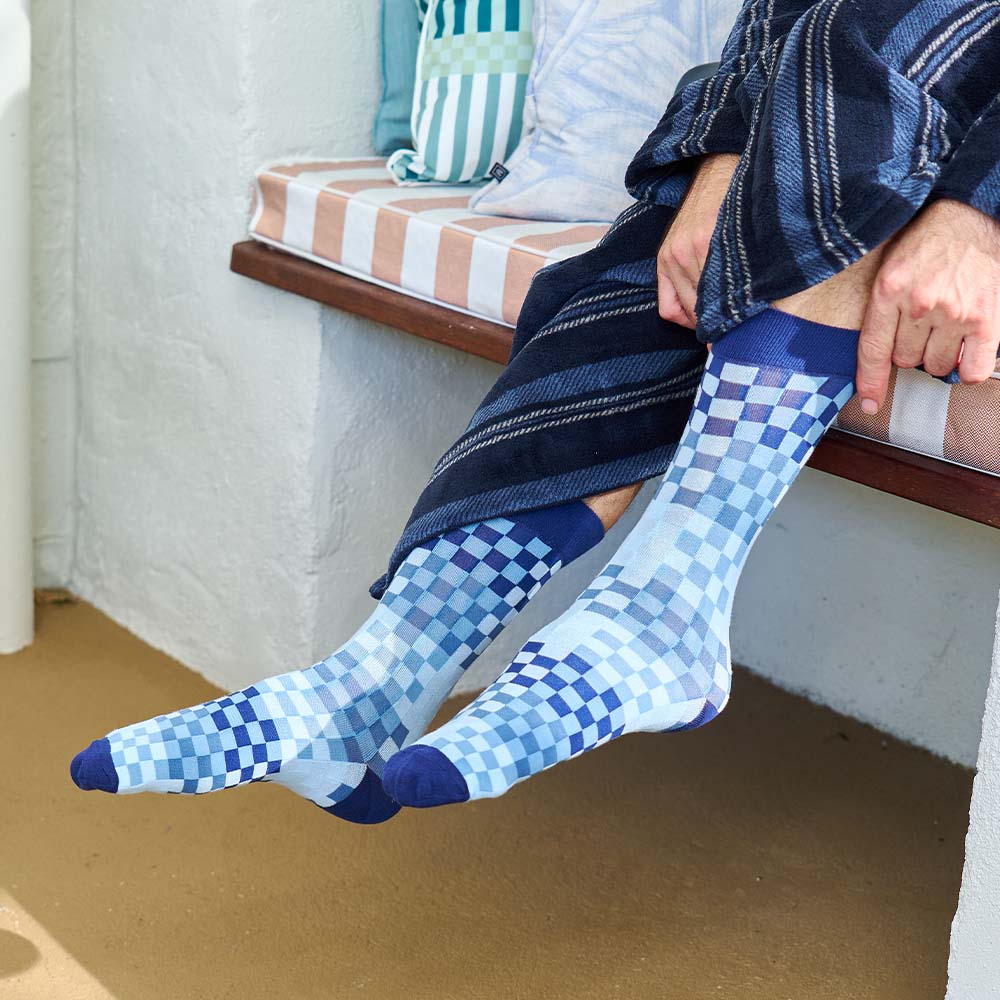 Person wearing blue checkered socks sitting on a bench.