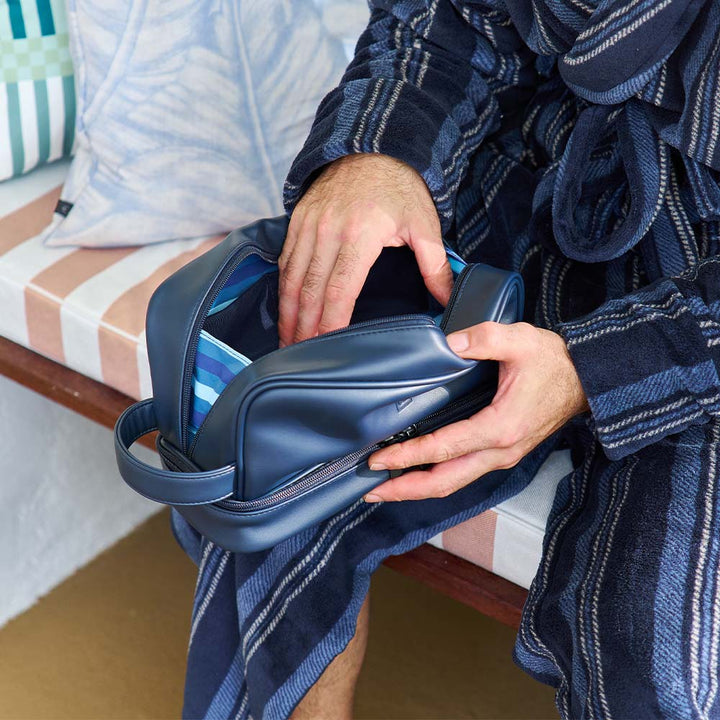 Person holding a blue shoe in a cozy indoor setting with striped cushions.